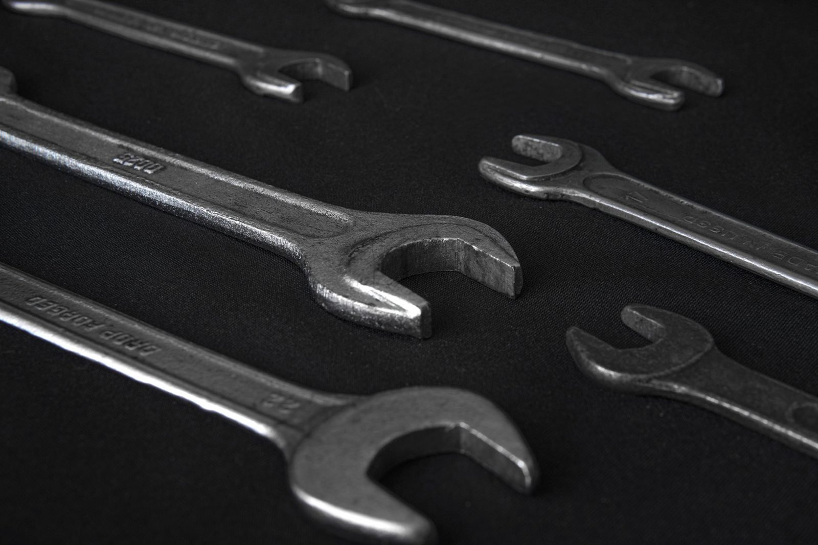 A set of open-ended spanners arranged on a dark surface