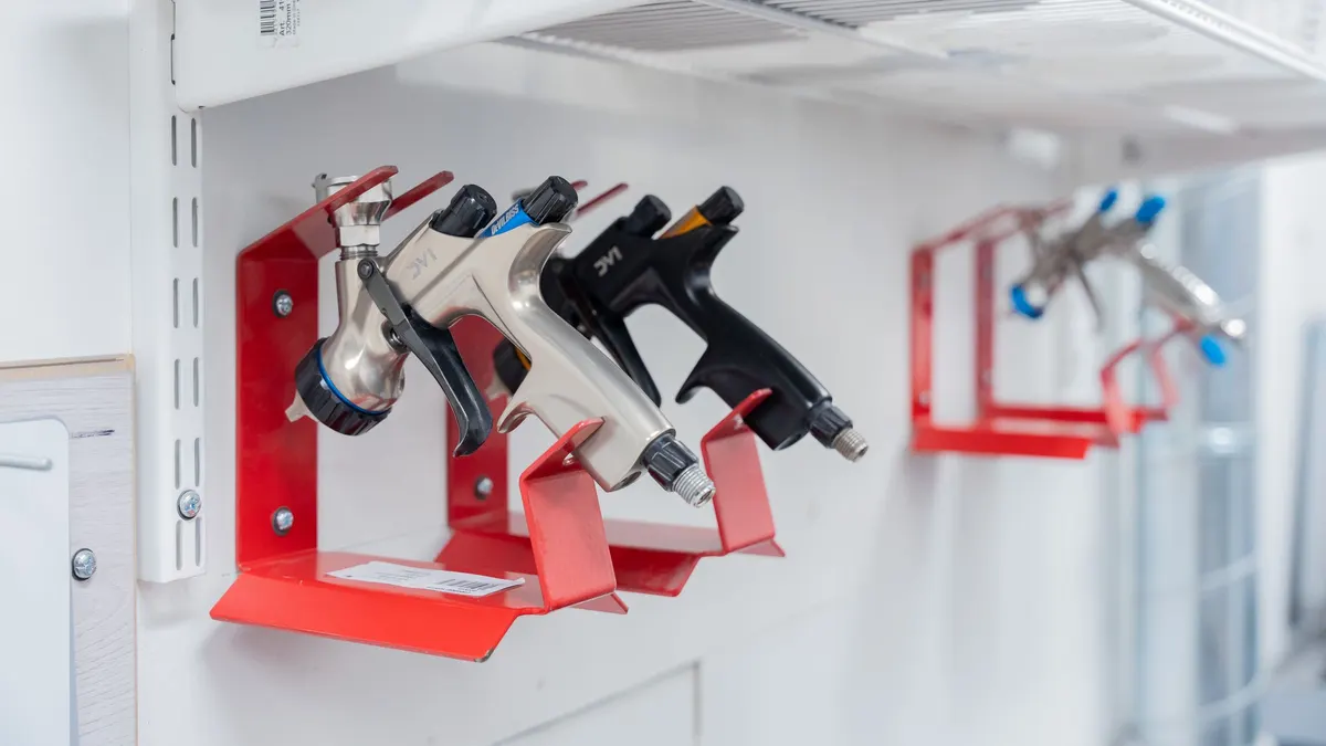 Air spray guns hanging on red wall brackets