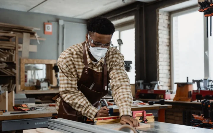 Woodworker wearing a mask at a table saw in a workshop