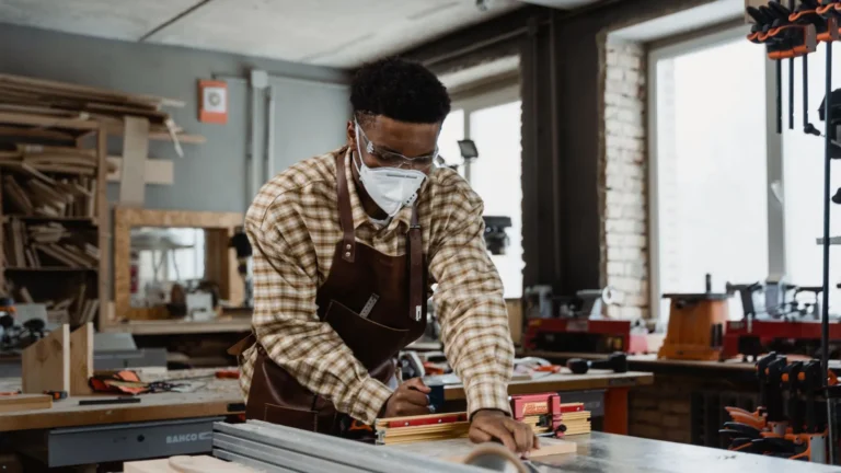 Woodworker wearing a mask at a table saw in a workshop