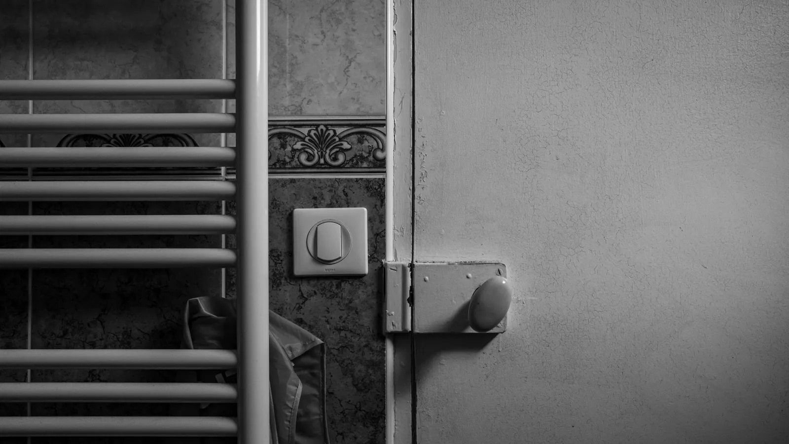 Wall-mounted heating panel beside a light switch on a gray wall