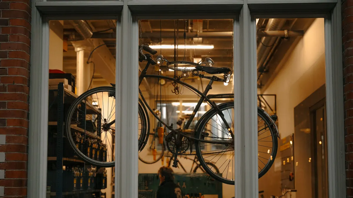 Bicycle hanging on a wall mount inside a workshop window