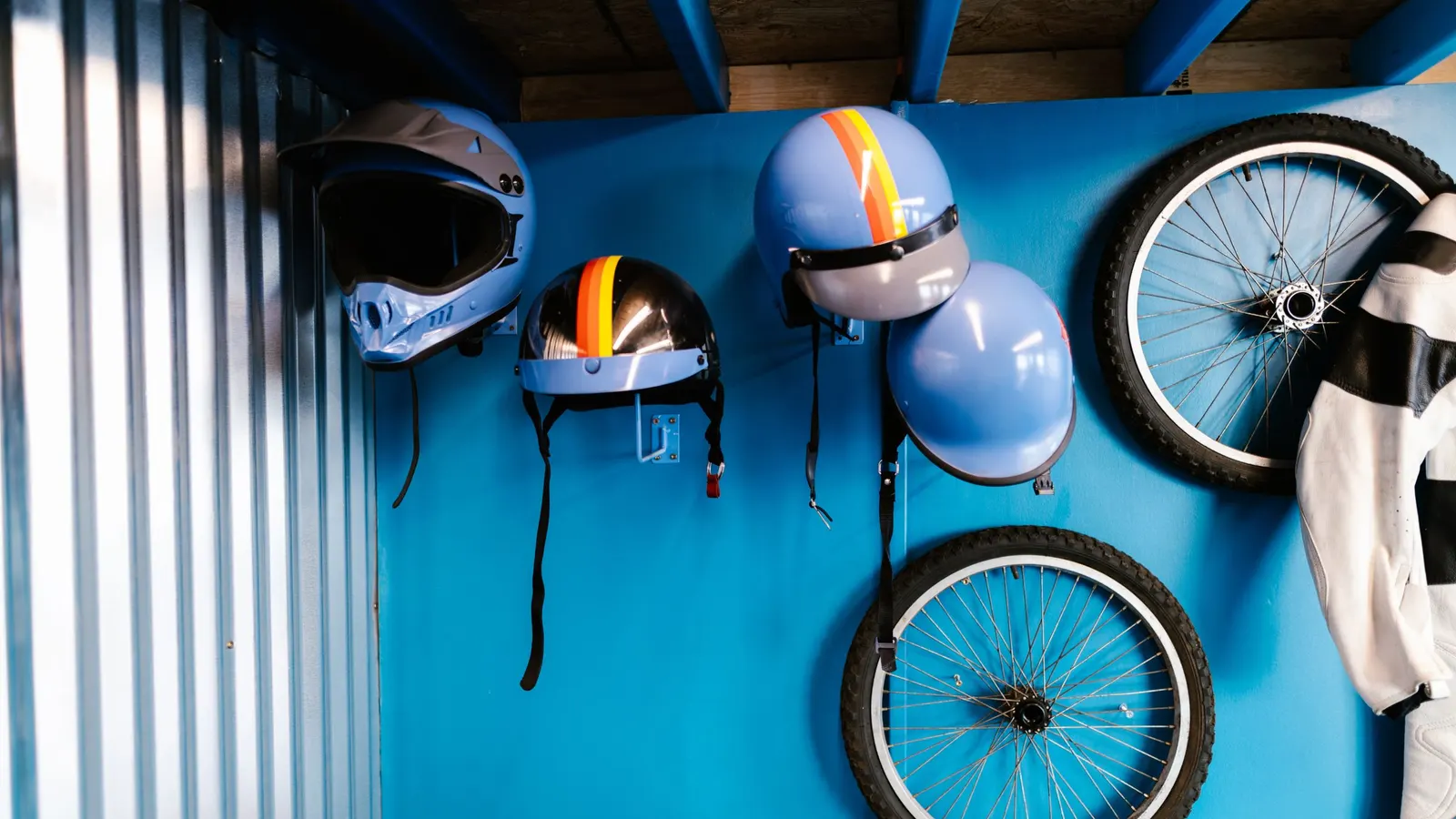 Bikes, wheels and helmets hanging on a blue wall
