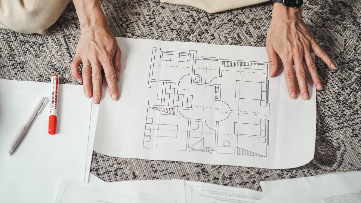 Hands spread out over a floor plan drawing