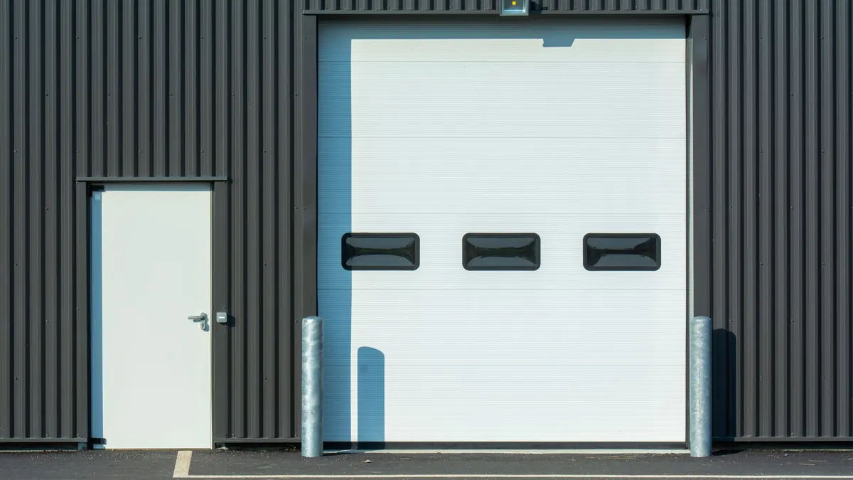 White sectional garage door with a row of windows next to a white walk-in door