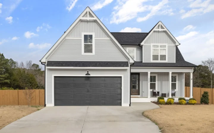 Gray two-story house with a dark double garage door and a concrete driveway