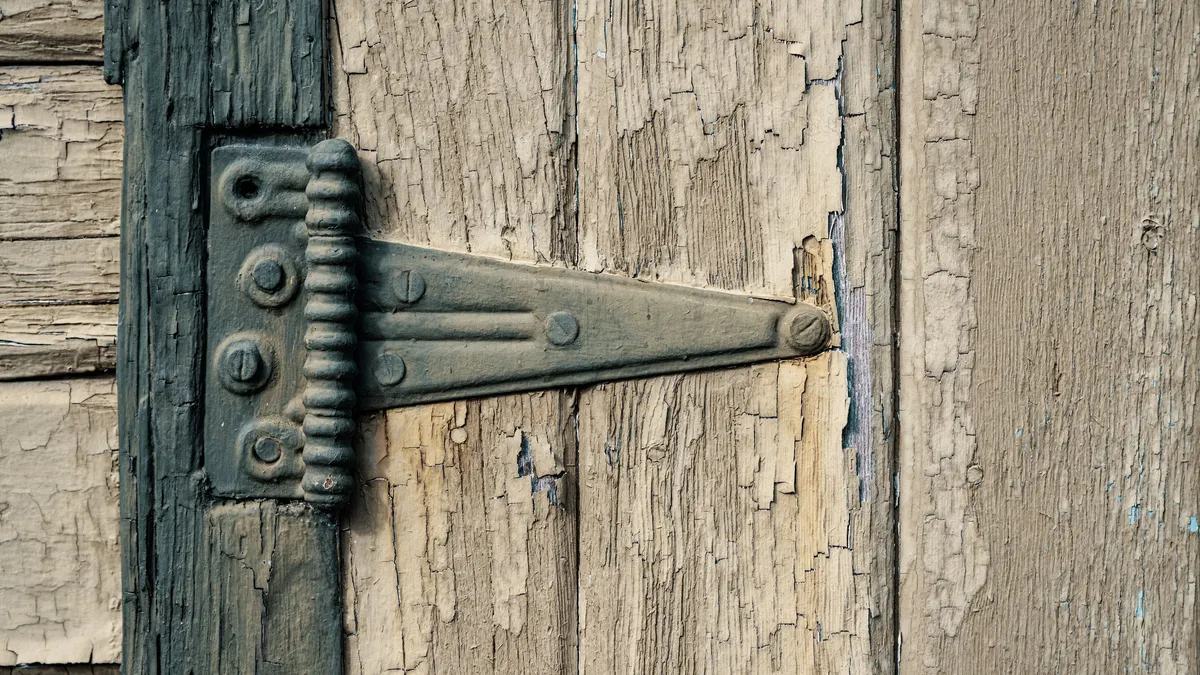 Close-up of an old metal strap hinge on a weathered wooden door