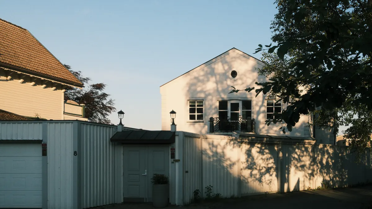 House in warm evening light behind a fence