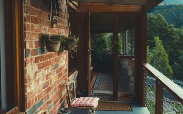 Screened porch beside a brick wall looking out to trees