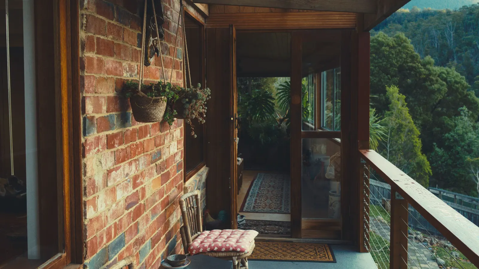 Screened porch beside a brick wall looking out to trees