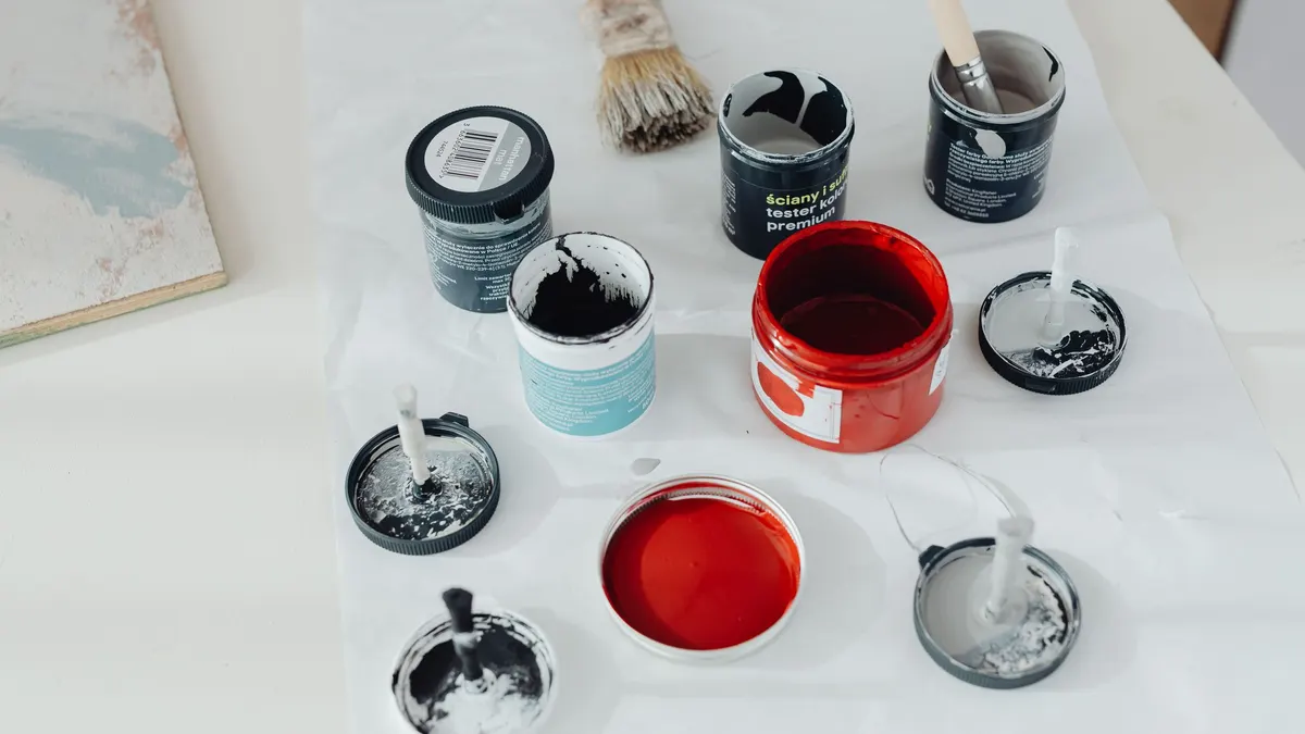 Several open cans of paint in different colors on a white surface