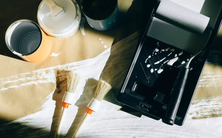 Open paint can, brushes and a roller tray on a drop cloth