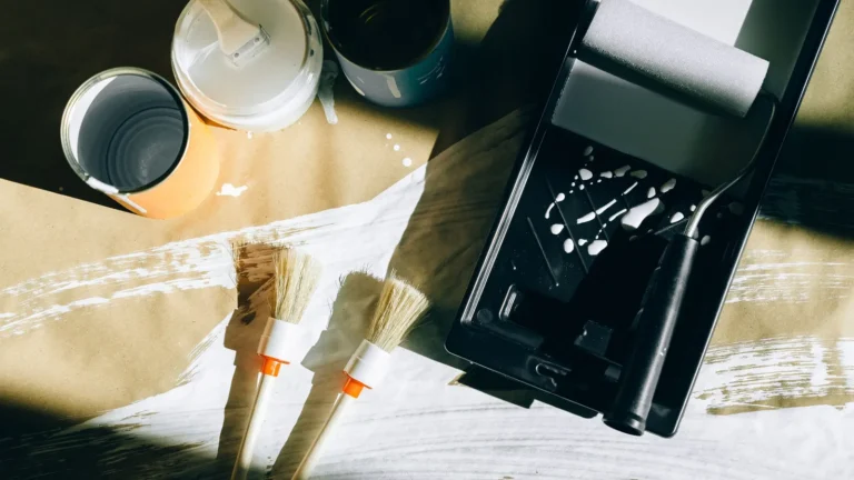 Open paint can, brushes and a roller tray on a drop cloth