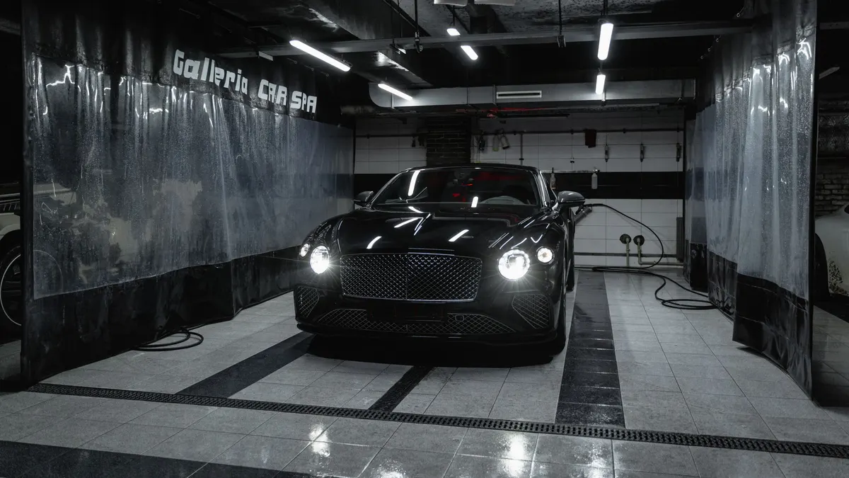 Car parked in a garage bay with a tiled floor and bright lights