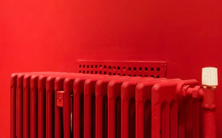 Red cast iron radiator against a red wall