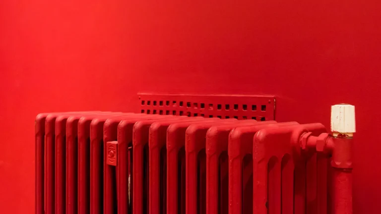 Red cast iron radiator against a red wall