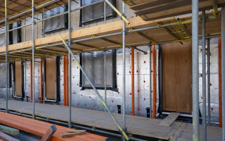 Building wall wrapped in insulation boards behind scaffolding