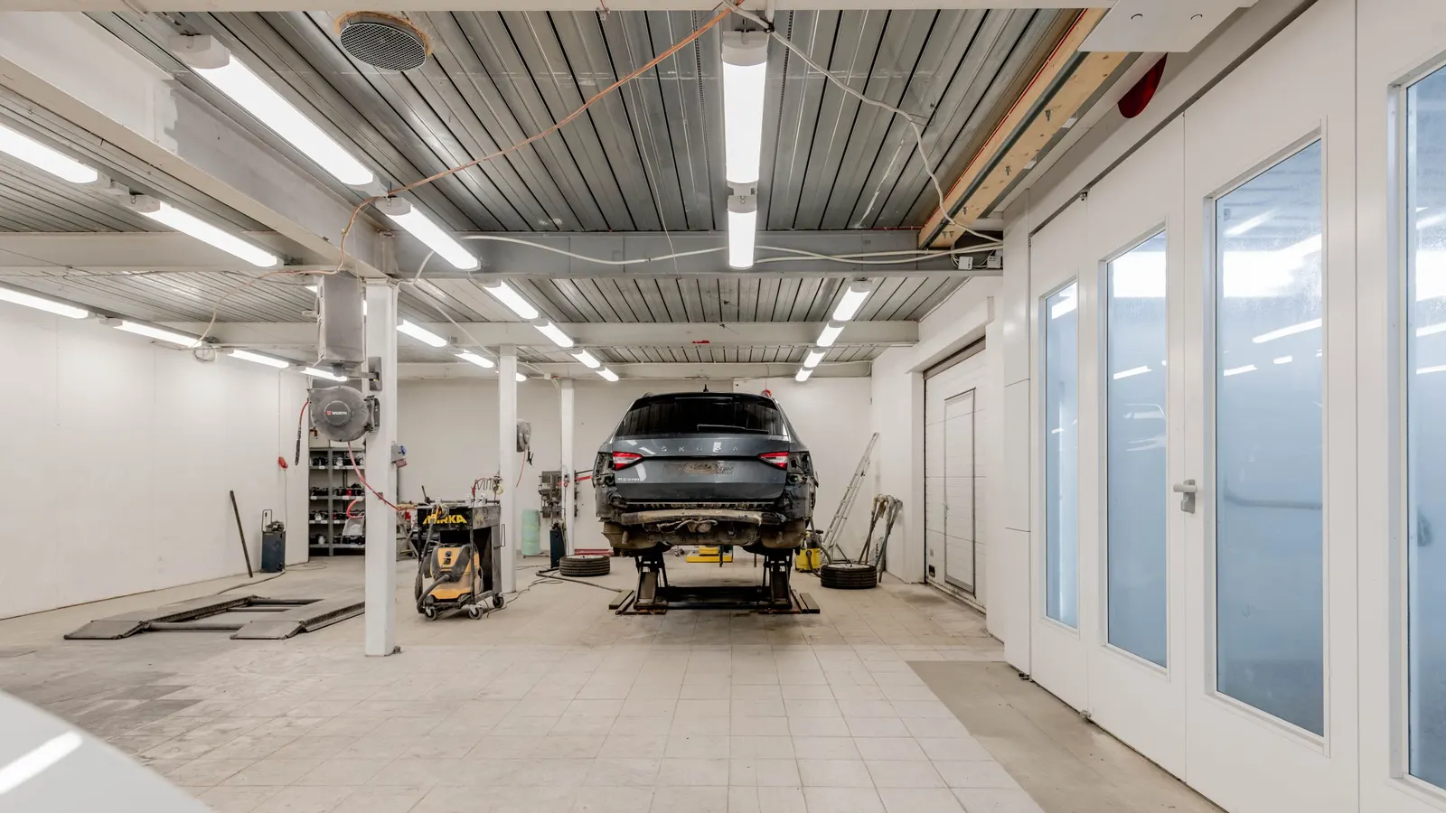 Bright garage with rows of LED ceiling lights and a raised car