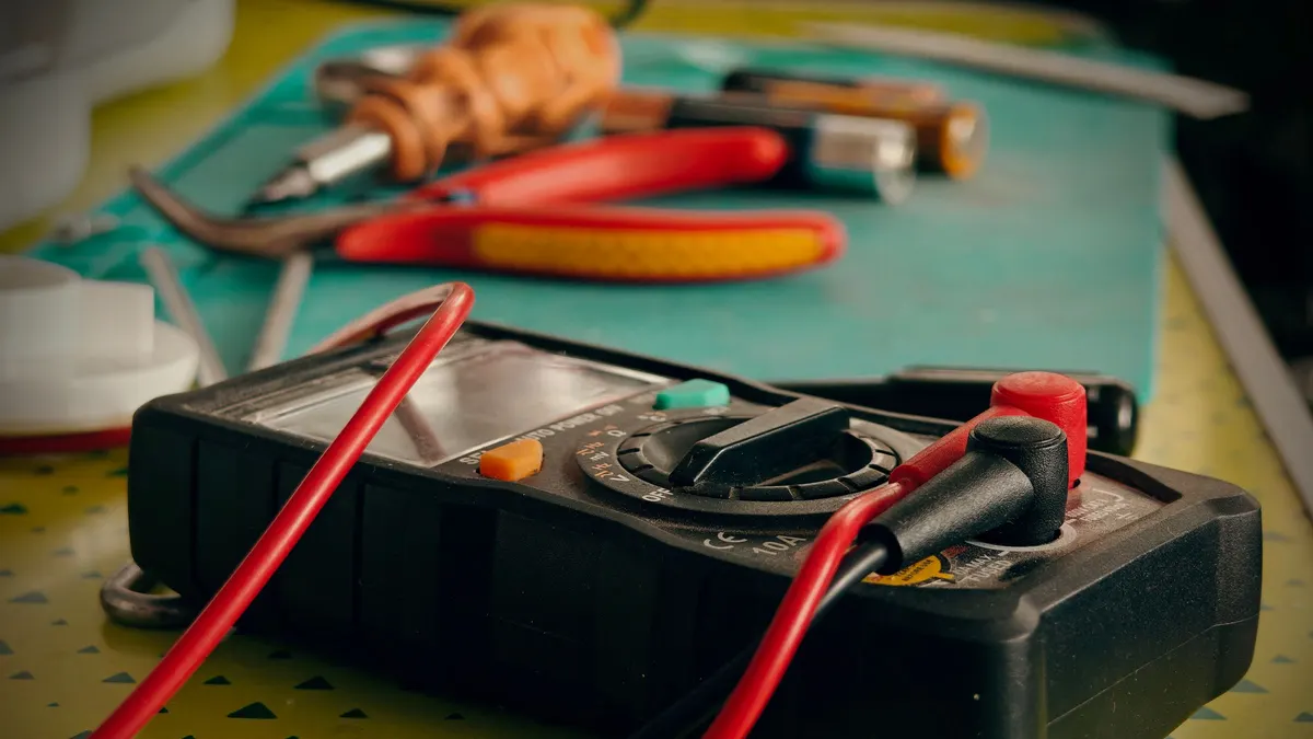 Digital multimeter with red and black test leads on a workbench