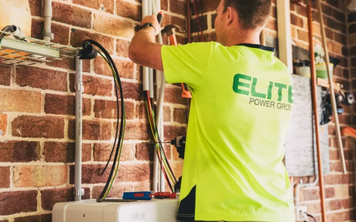 Technician in a work shirt fitting wiring on a brick wall