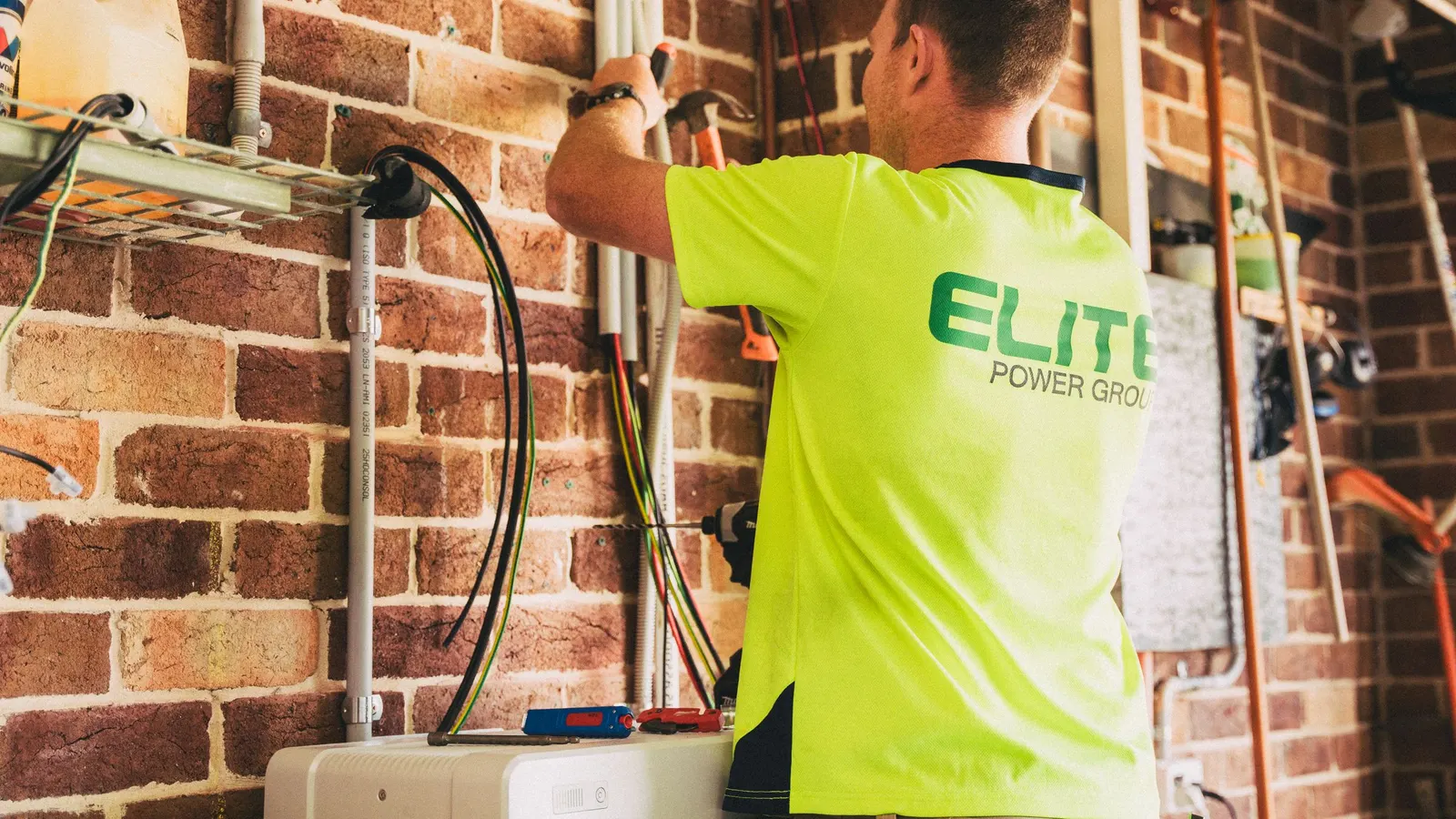 Technician in a work shirt fitting wiring on a brick wall