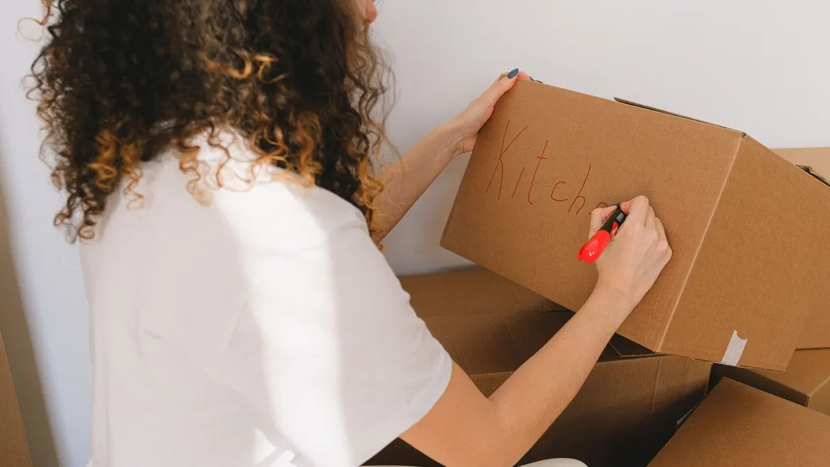 Person writing a label on a cardboard box