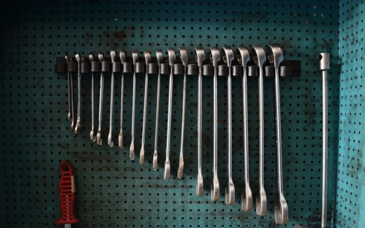 Wrenches hanging in size order on a teal pegboard