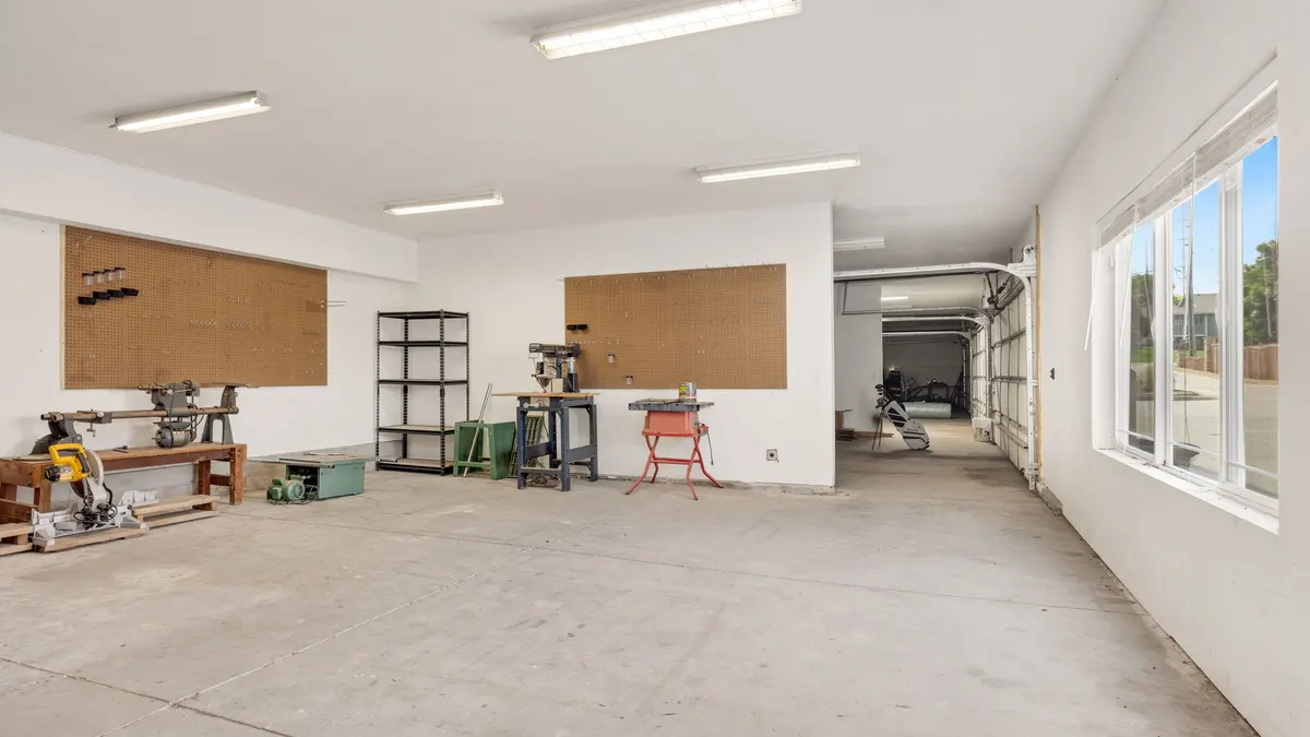 Bright renovated garage workshop with white walls and boards on the wall