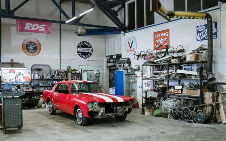 Garage with a red classic car, shelving and signs on the walls