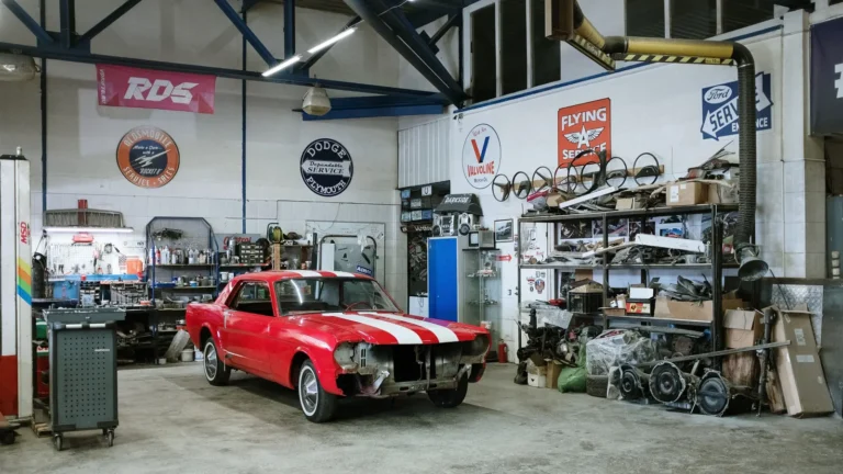 Garage with a red classic car, shelving and signs on the walls