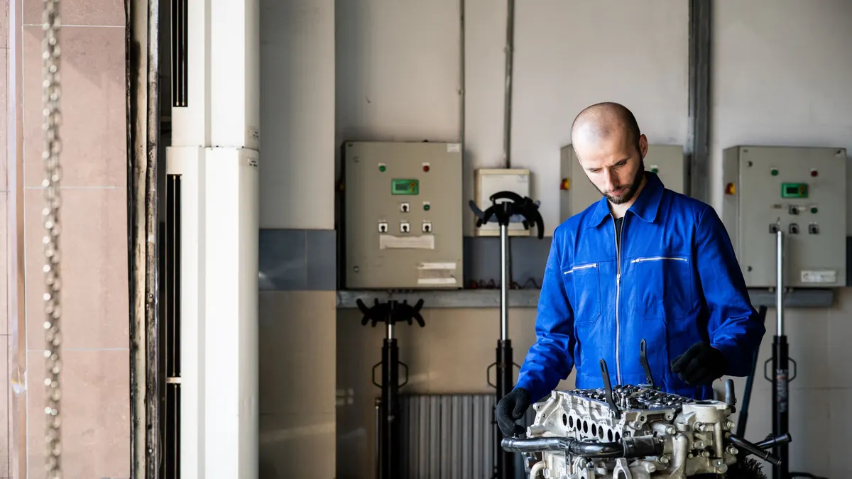 Technician in a blue uniform working at a repair bench