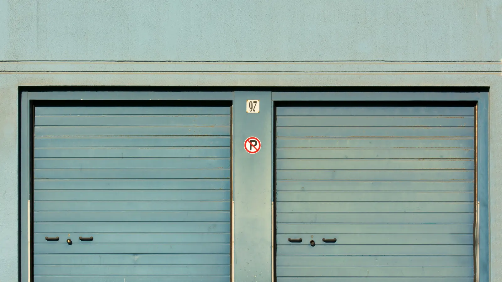 Two teal sectional garage doors side by side