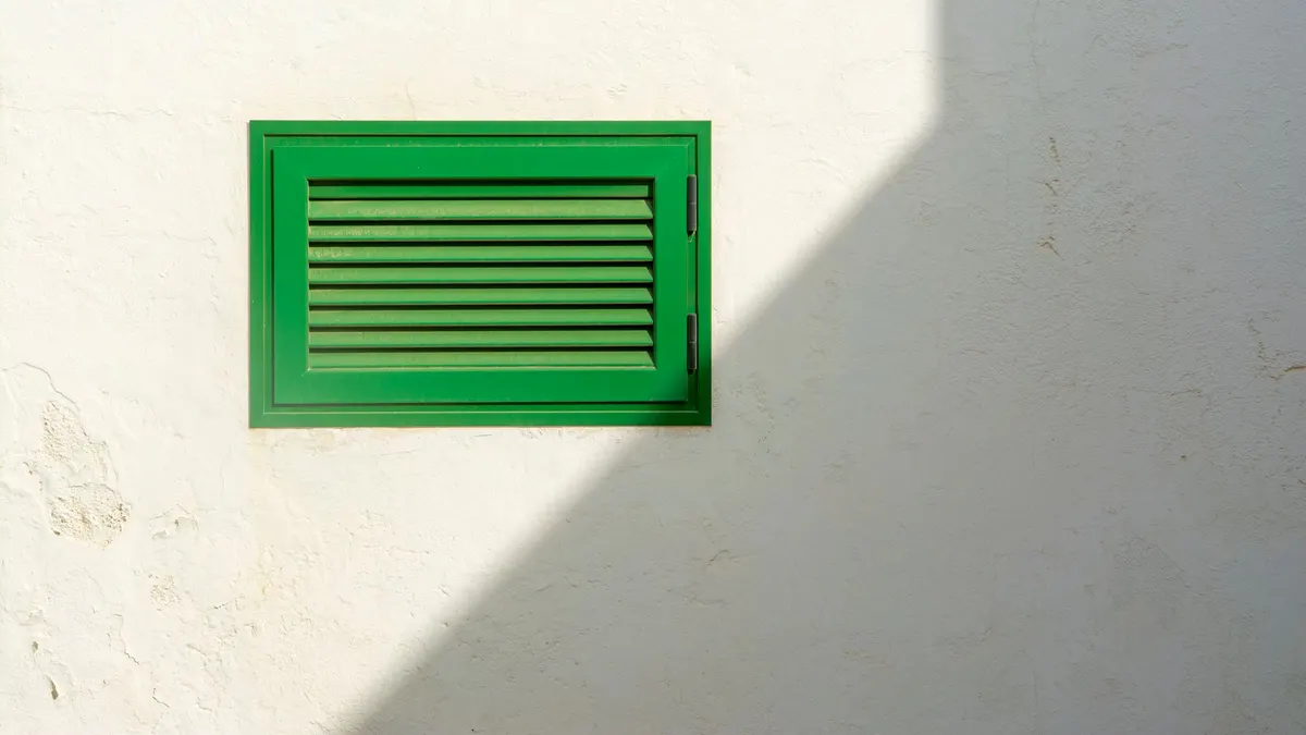 Green louvered vent on a white wall