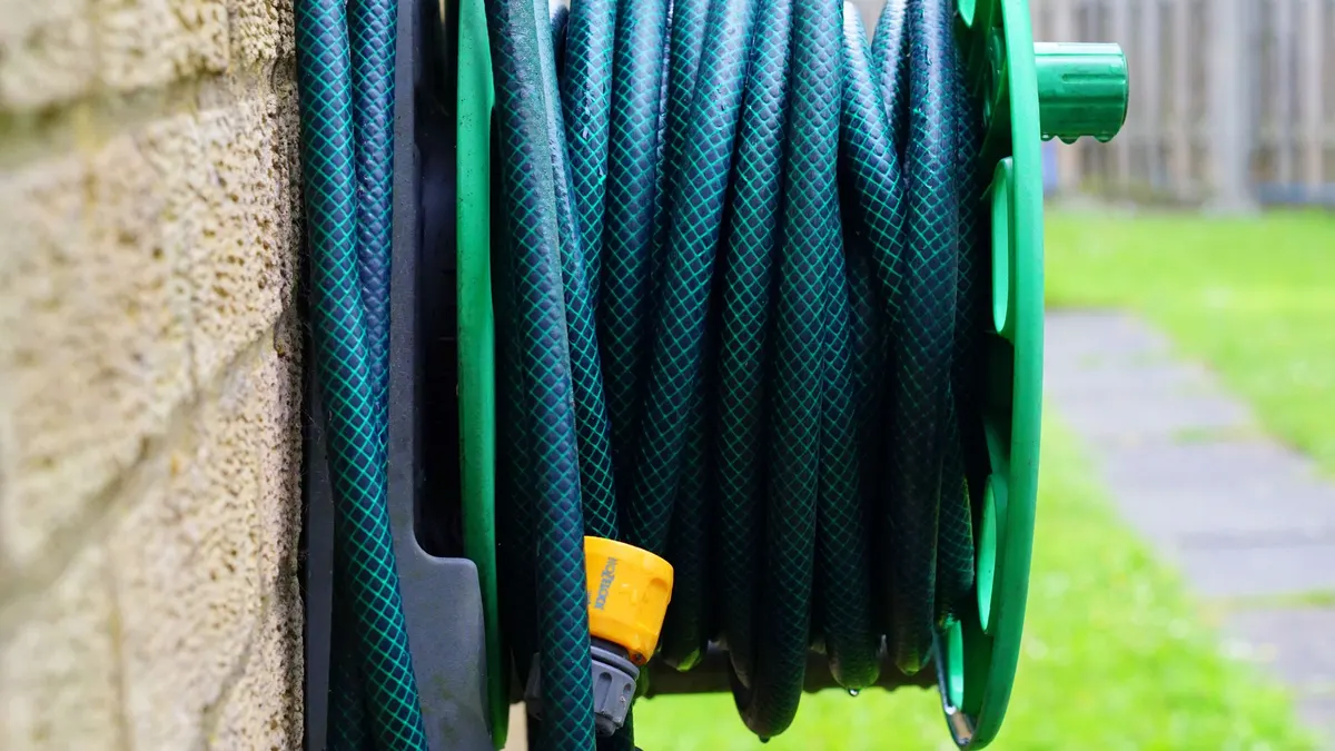 Green garden hose coiled on a wall-mounted reel