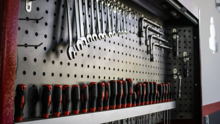 Black pegboard holding wrenches and screwdrivers above a shelf