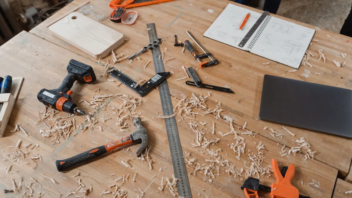 Workbench top with a hammer, clamps, a drill and wood shavings
