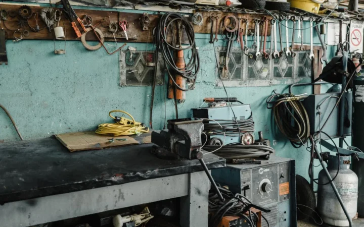 Workbench with a vise and tools against a teal workshop wall