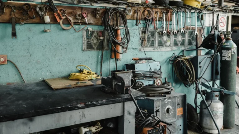 Workbench with a vise and tools against a teal workshop wall