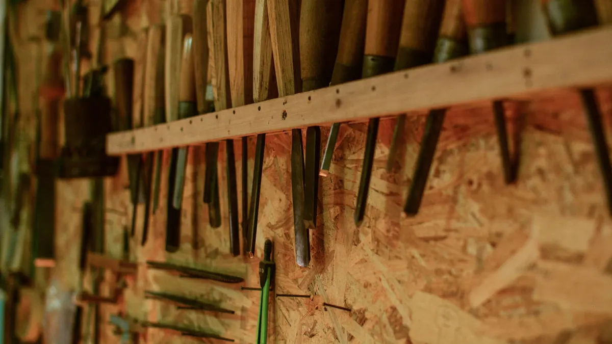 Row of hand tools hanging on a workshop wall rack