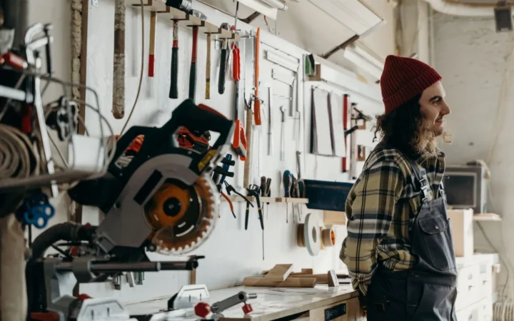 Craftsman standing in a workshop with tools mounted on the wall