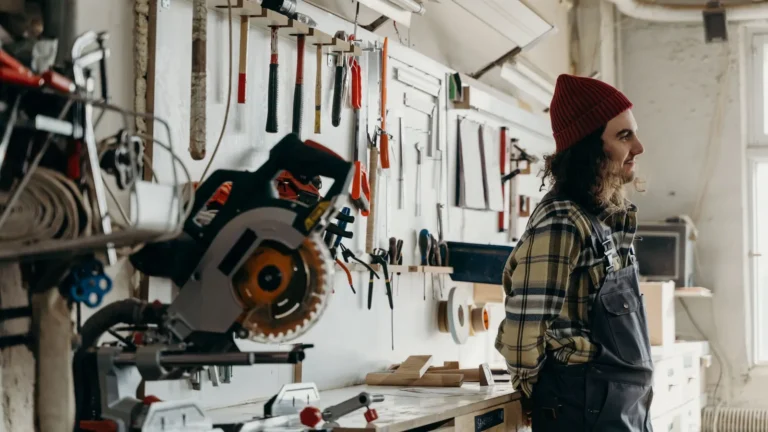 Craftsman standing in a workshop with tools mounted on the wall