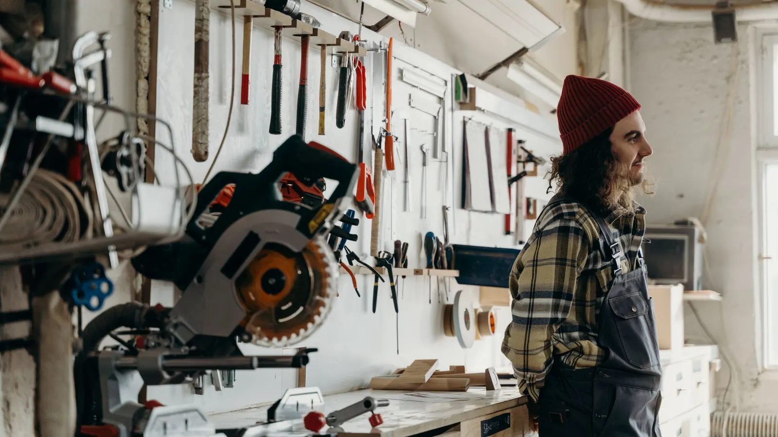 Craftsman standing in a workshop with tools mounted on the wall