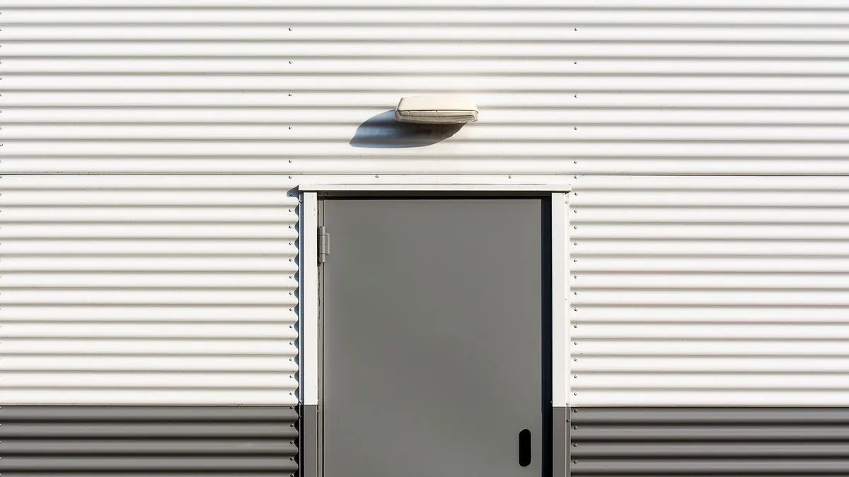 Gray metal door set into a ribbed metal wall