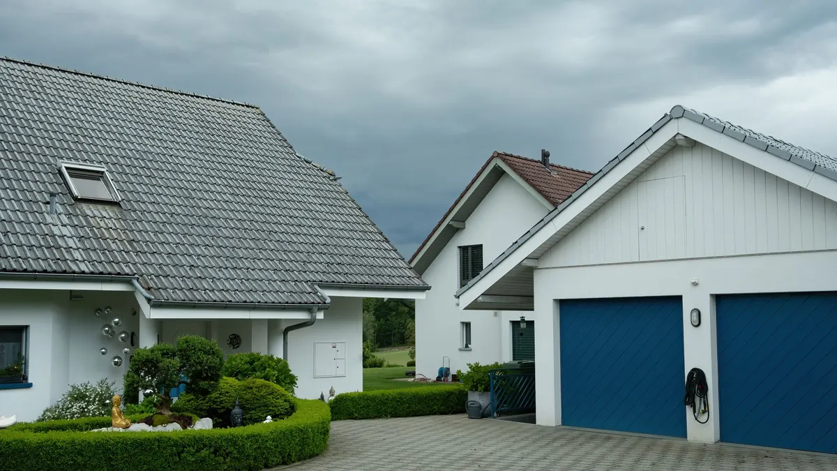 Two-story house with blue garage doors and a paved driveway