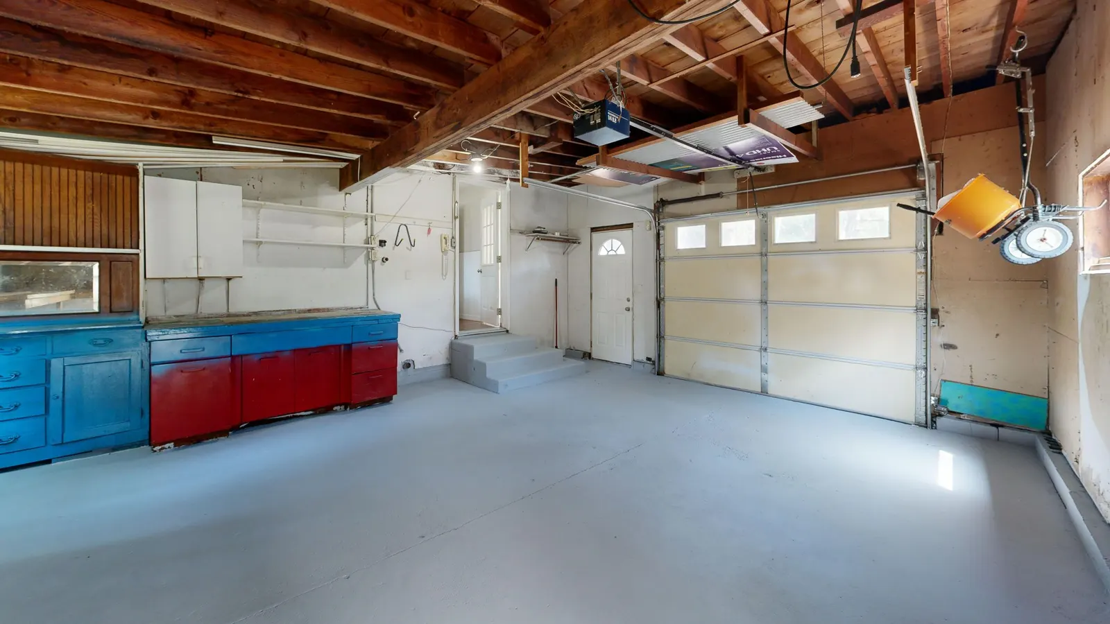 Clean garage interior with a smooth gray floor, cabinets and a closed garage door