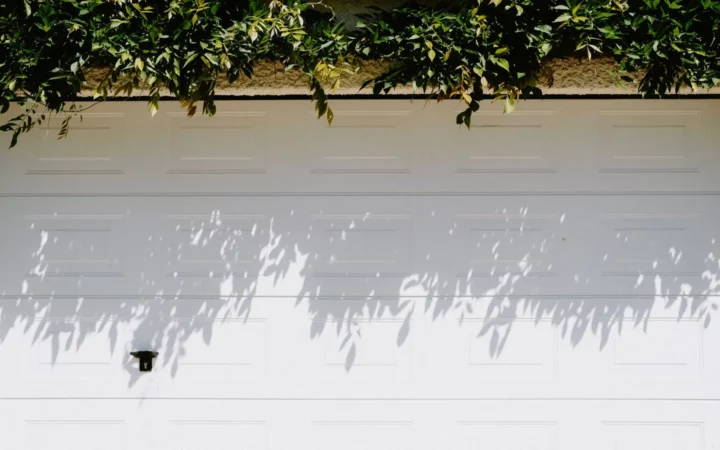 White insulated garage door with leaf shadows across its panels