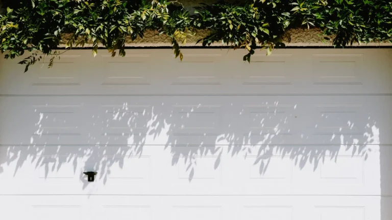 White insulated garage door with leaf shadows across its panels