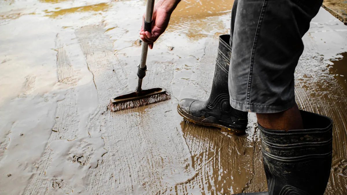 Worker in boots spreading coating across a floor with a squeegee