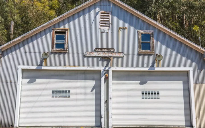 Gray building with two white single garage doors