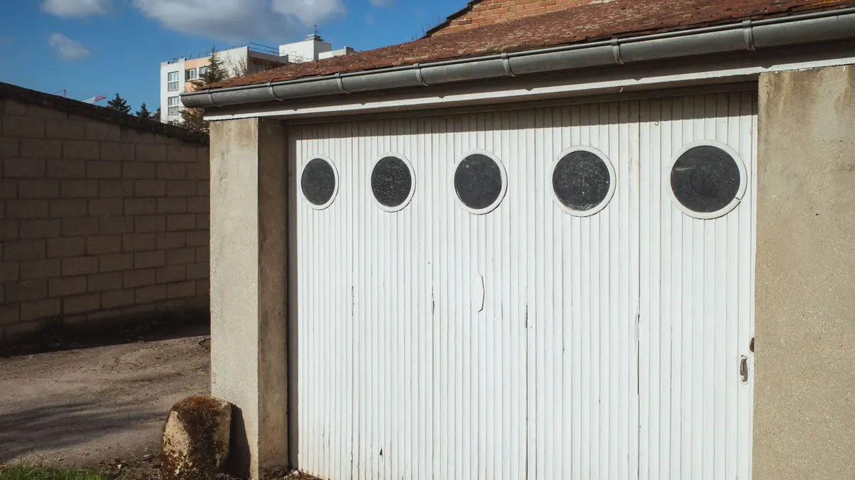 White garage door with round windows beside a driveway